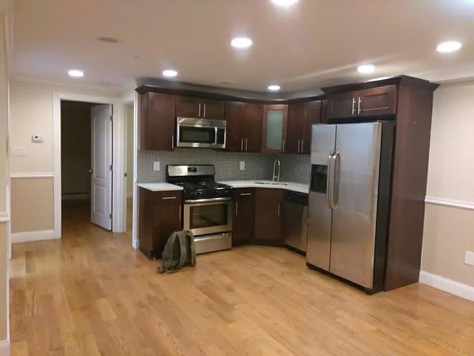Completed kitchen with dark cabinetry, stone counters and wood flooring