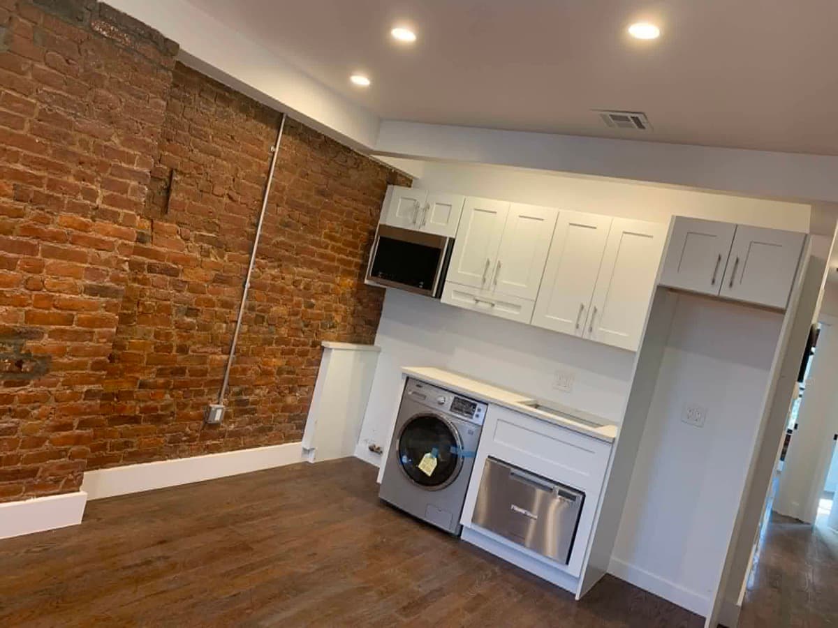 Kitchen remodeling work with white cabinets and exposed brick