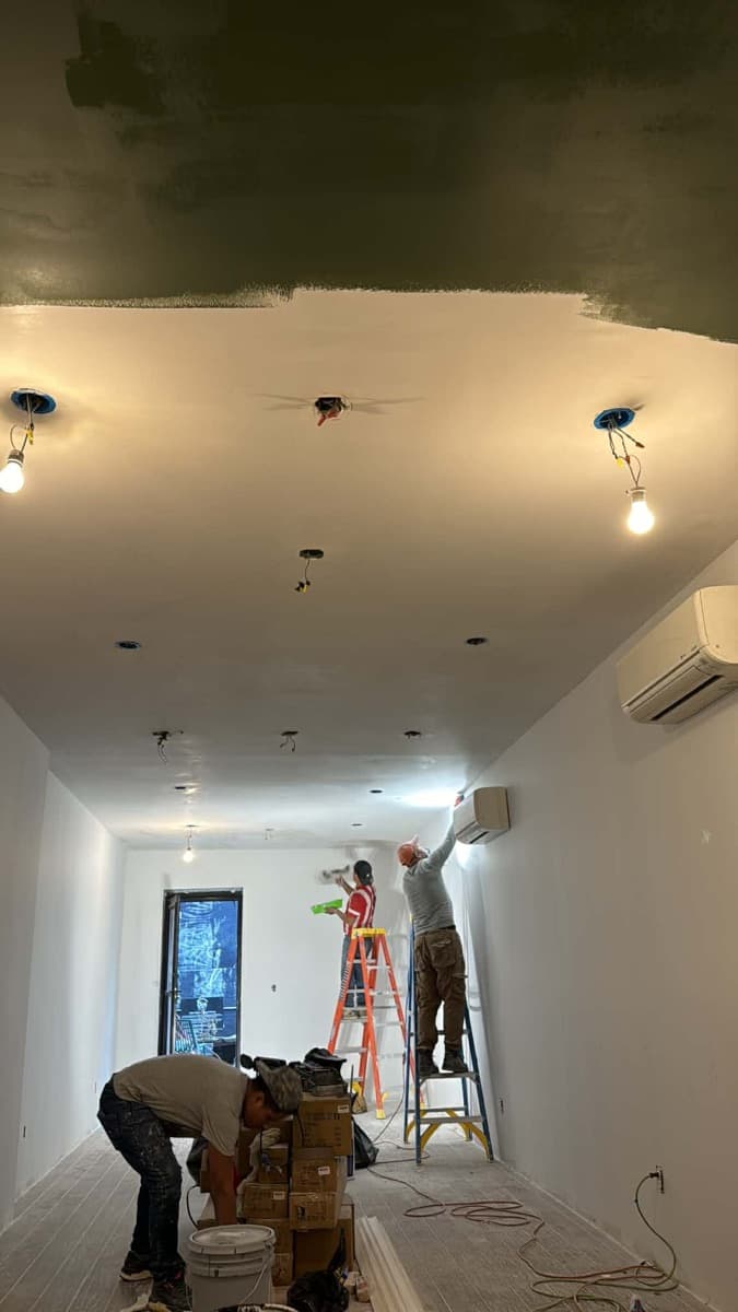 Crew preparing and painting an interior ceiling during renovation