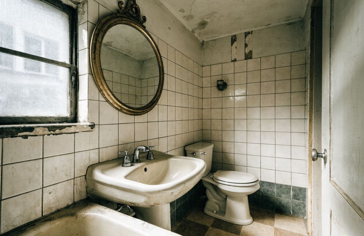 Illustrative outdated bathroom with old tile and worn finishes