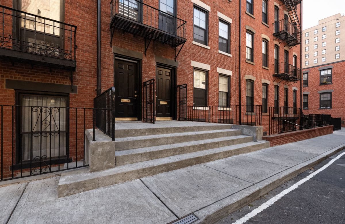 Illustrative multifamily rowhouse with a new concrete sidewalk and steps