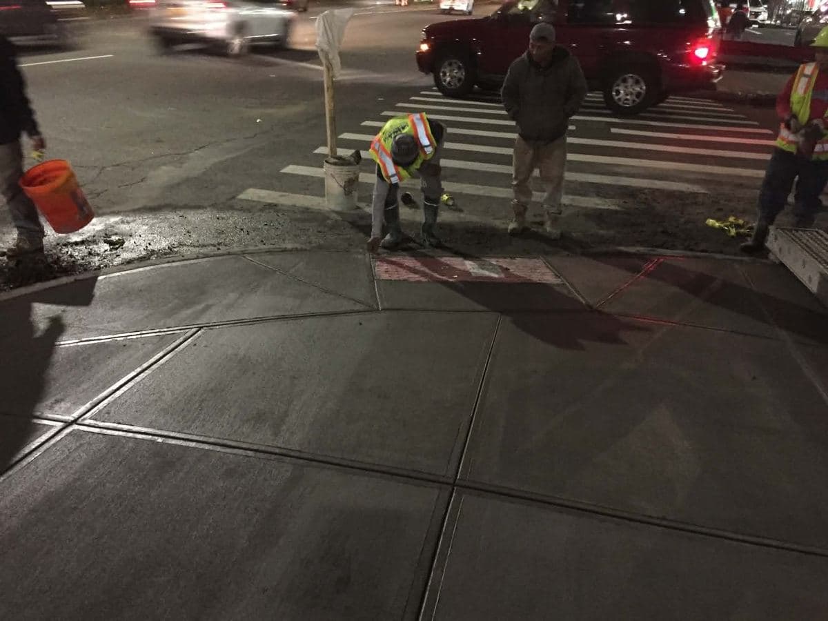 Fresh concrete surface being finished beside an active street