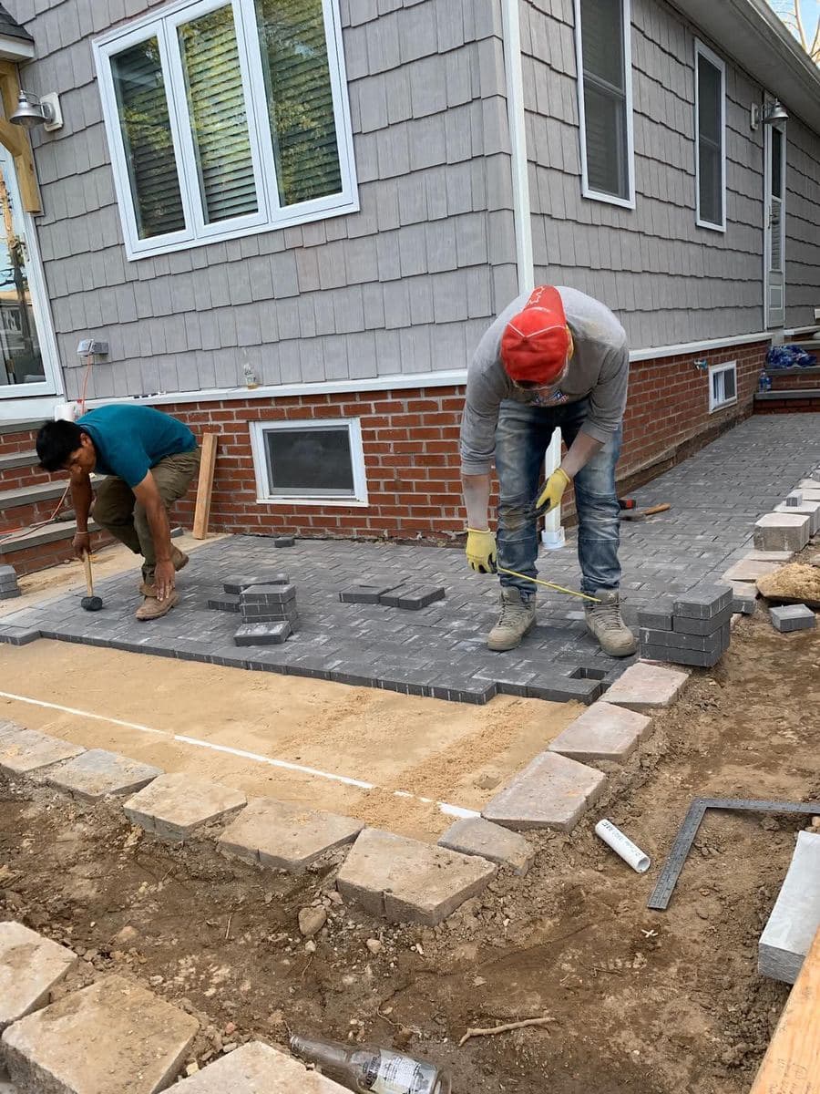 Worker addressing an exterior concrete surface beside a house
