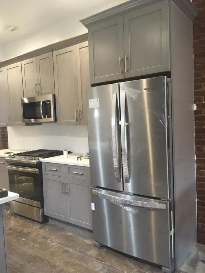 Gray kitchen cabinetry fitted around stainless steel appliances