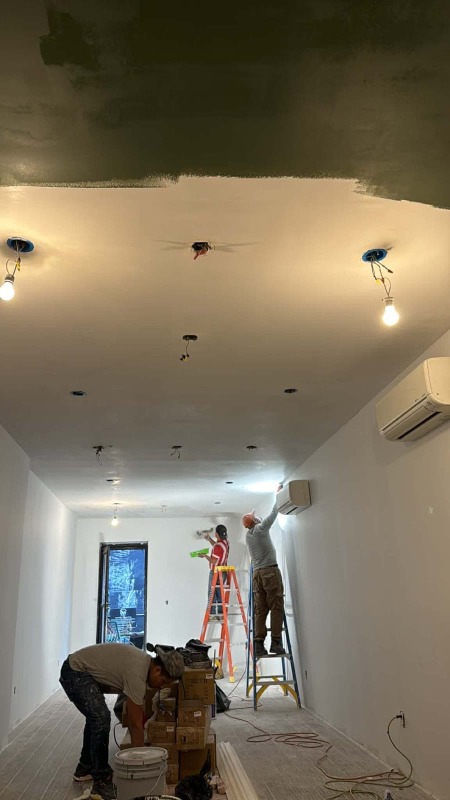 Painting crew applying a finish coat to an interior ceiling and walls