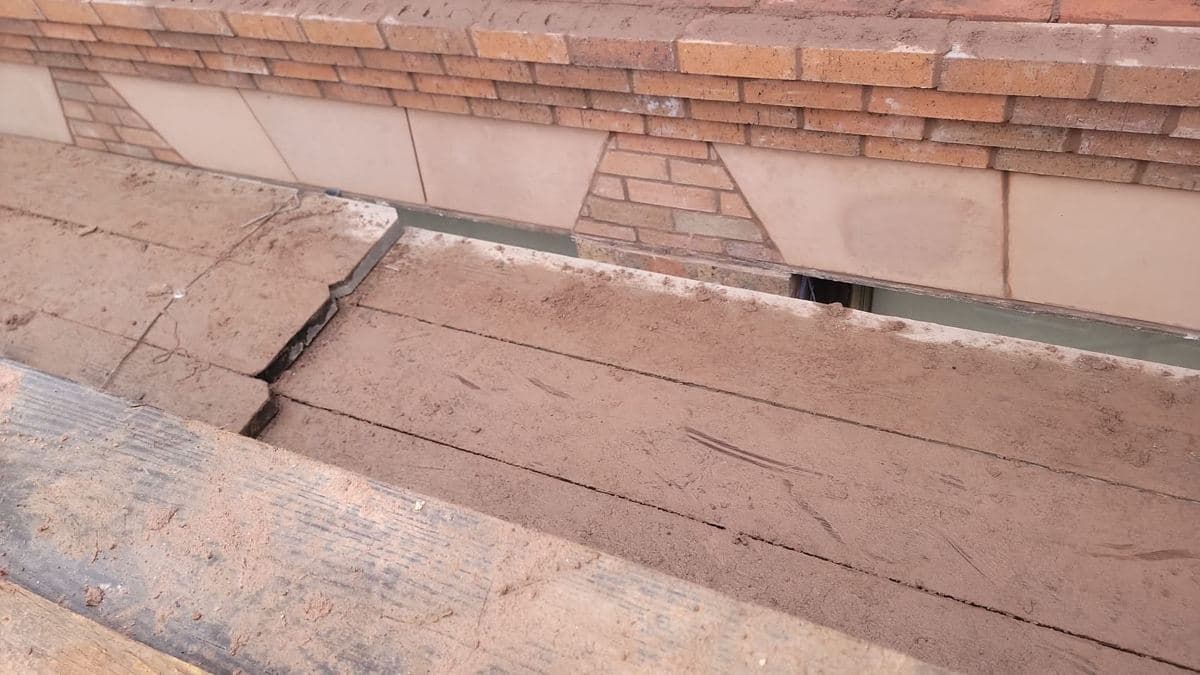 Open crack running along the masonry joint of a parapet wall